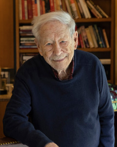 Portrait of Mike Blumenthal standing in front of a bookshelf
